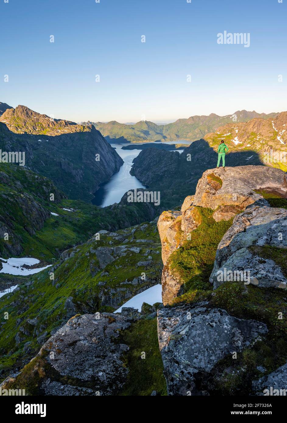 Wanderer, junge Frau, die auf Felsen steht und in die Ferne blickt, Fjord mit Bergen, Wandern zum Trollfjord Hytta, am Trollfjord und Raftsund Stockfoto