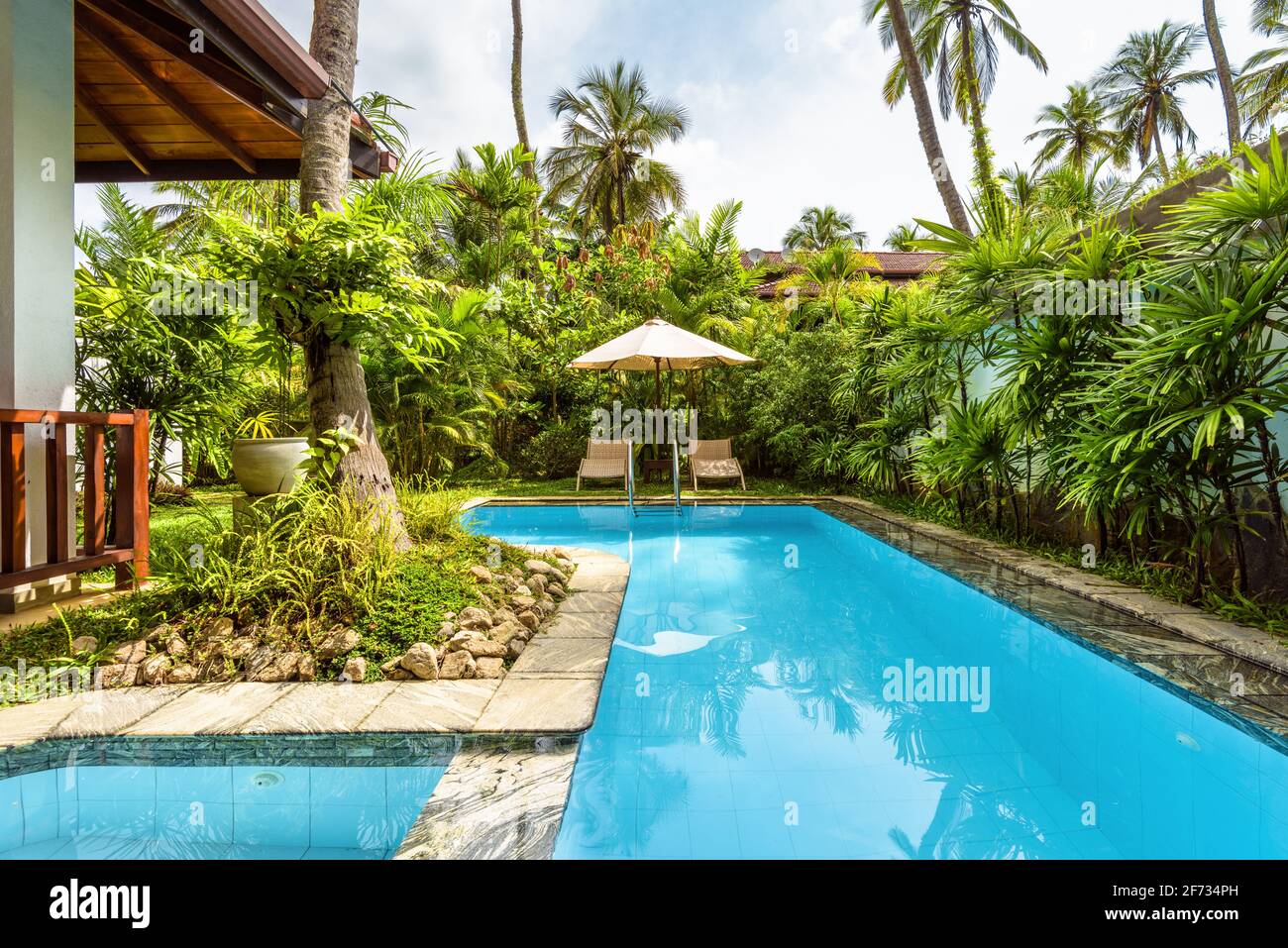 Pool mit Sonnenschirm und Strandliegen im tropischen Hotel oder Ferienhaus. Schöner Pool im Innenhof des Wohnhauses. Landschaftsdesign von b Stockfoto