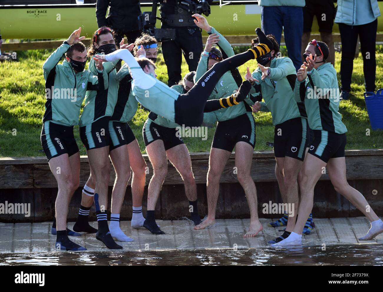 Die Cambridge Crew feiert, indem sie ihre cox nach dem Gewinn des 166. Herrenbootrennens auf dem Fluss Great Ouse in der Nähe von Ely in Cambridgeshire in den Fluss wirft. Bilddatum: Sonntag, 4. April 2021. Stockfoto