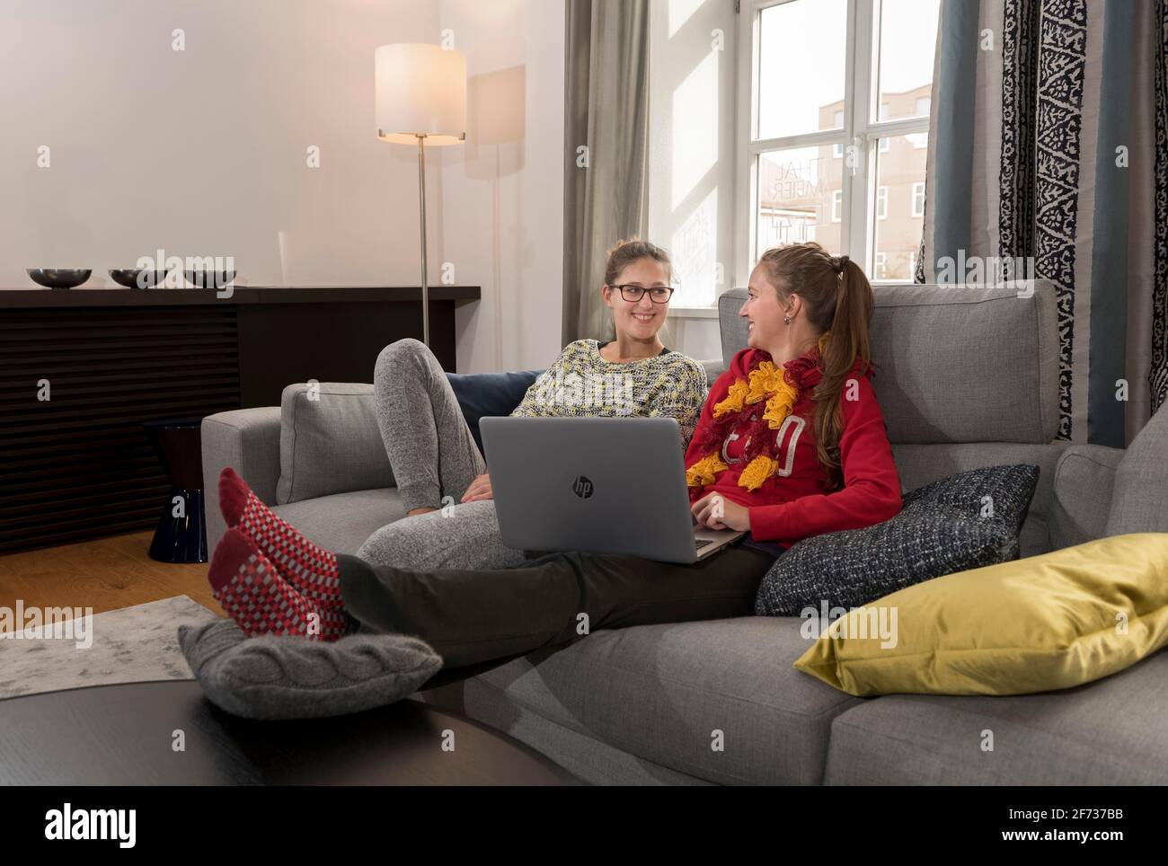 Zwei junge Frauen, die mit einem Laptop auf einem Sofa sitzen Stockfoto