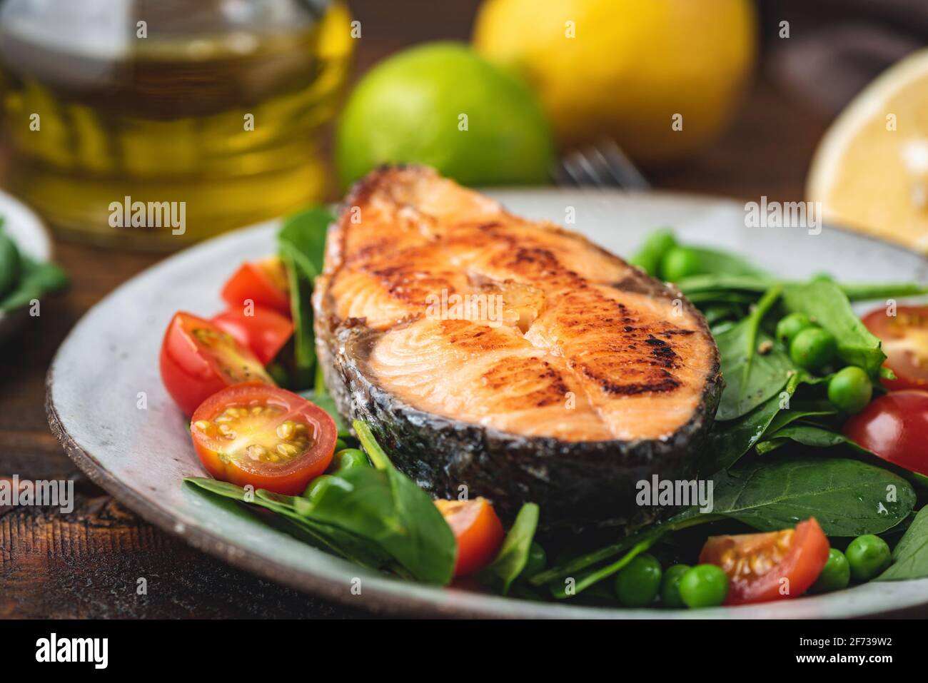 Geröstetes Lachssteak mit Spinat und Tomatensalat auf einem Teller, Nahaufnahme Stockfoto