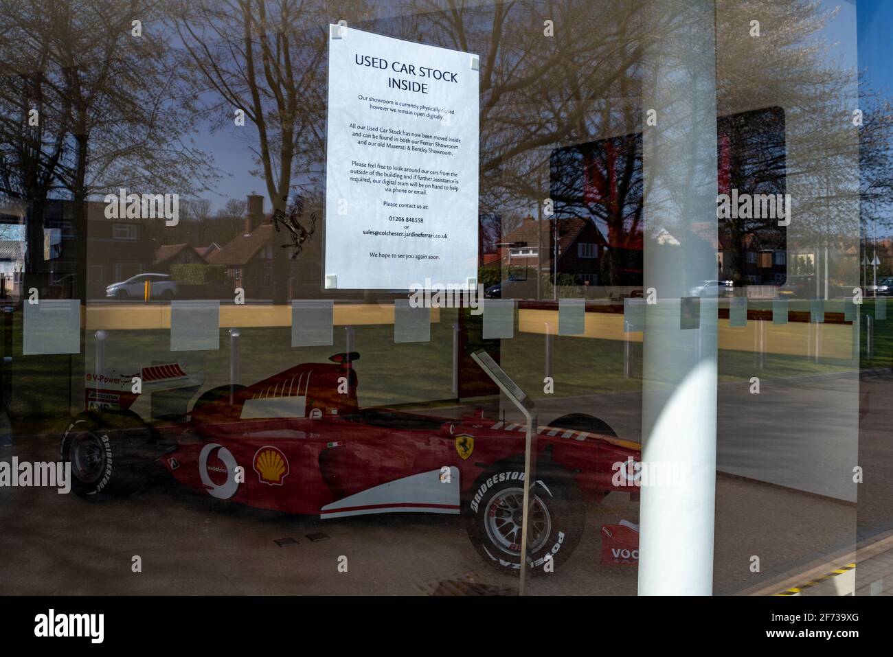 Ferrari F1 Grand Prix-Rennwagen in einem Autohaus in Colchester, Essex, Großbritannien, mit Hinweis auf Gebrauchtwagenbestand. Humor. Gegenüberstellung von Zeichen Stockfoto