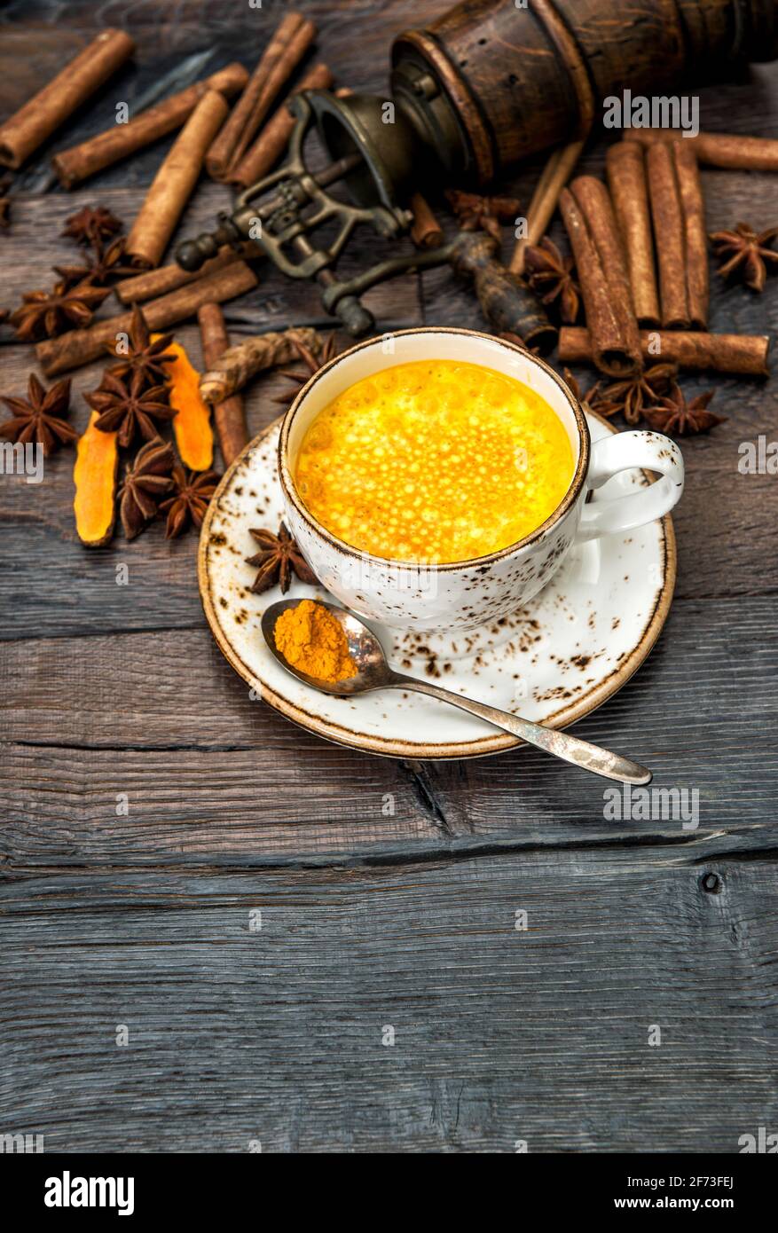 Heißes Kurkuma-Getränk. Goldene Milch mit Gewürzen auf dunklem Holzhintergrund Stockfoto