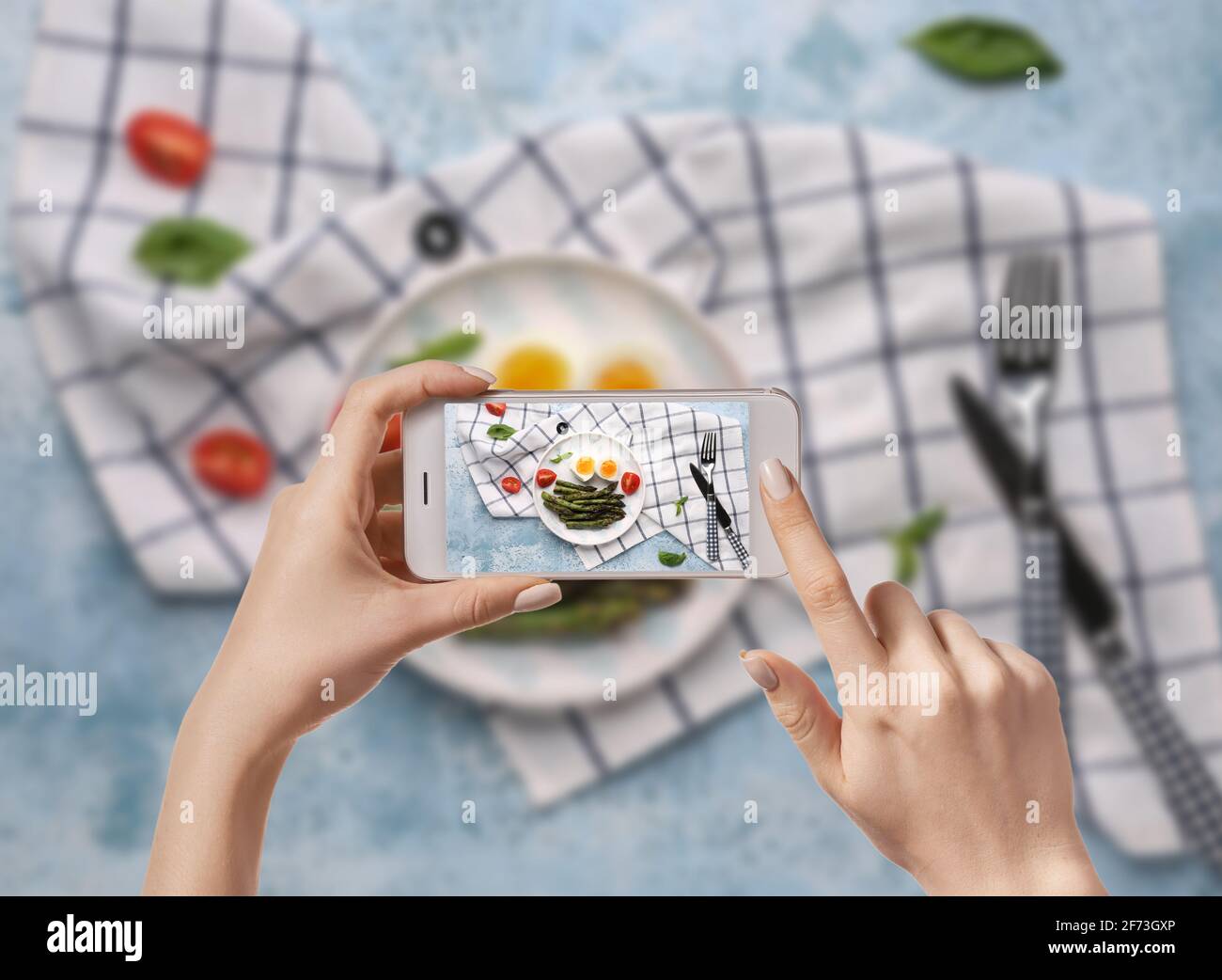 Fotografin für Lebensmittel mit Mobiltelefon, das leckere gekochte Eier mit Spargel fotografiert, Draufsicht Stockfoto