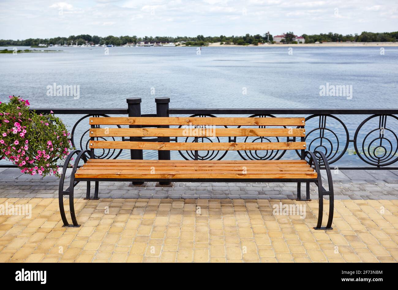 Böschung mit Bank mit Blick auf das Meer. Parken Sie die Holzbank auf dem gepflasterten Bürgersteig Stockfoto