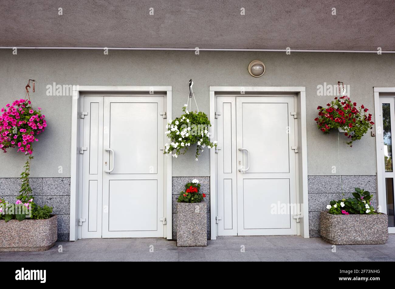 Weiße Eingangstüren zum Gebäude. Moderner Eingang mit Lampe und Blumentöpfen Stockfoto