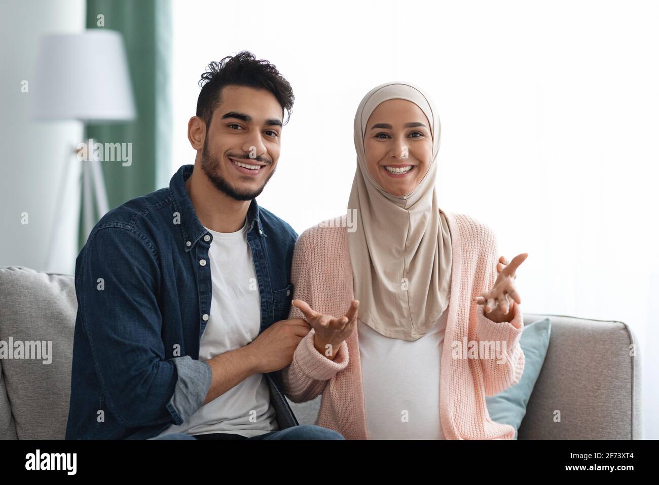 Frohe Nachrichten. Fröhliches, Schwanger-Muslimisches Paar, Das Vor Der Kamera Spricht Und Eine Schwangerschaftsankündigung Macht Stockfoto