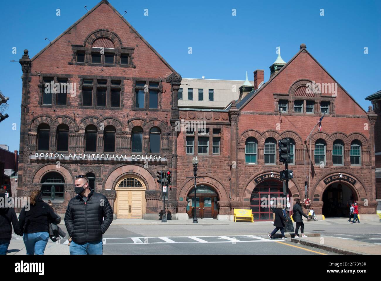 Menschen in Masken gehen vor dem historischen Gebäude. Stockfoto