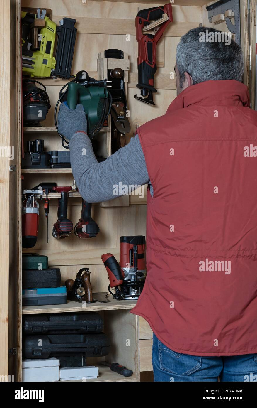 Mann, der an seinem selbstgemachten Werkzeugschrank arbeitet Stockfoto