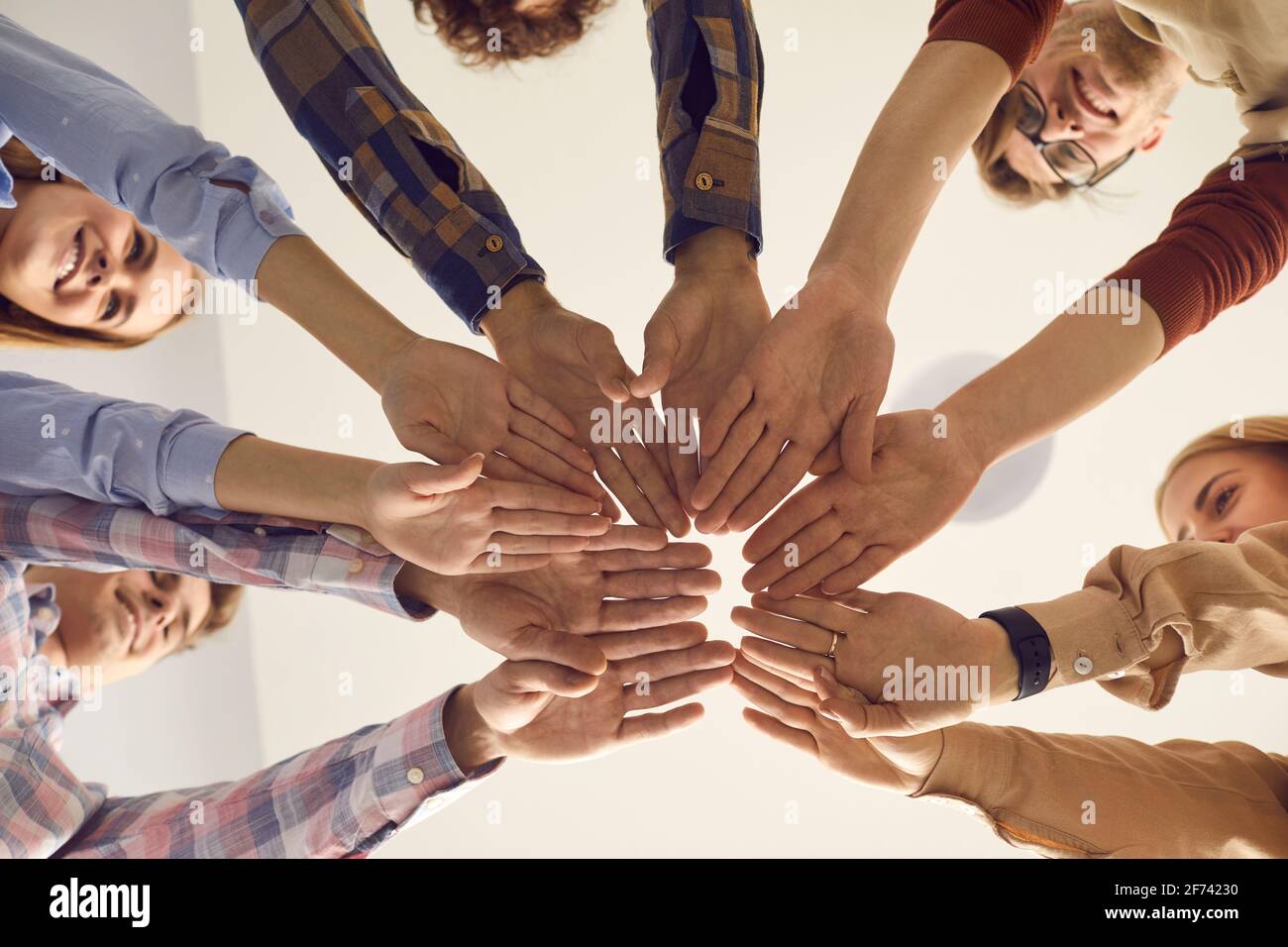 Nahaufnahme der Unteransicht von Personen, die die Hände im Stehen zusammenlegen Im Kreis Stockfoto