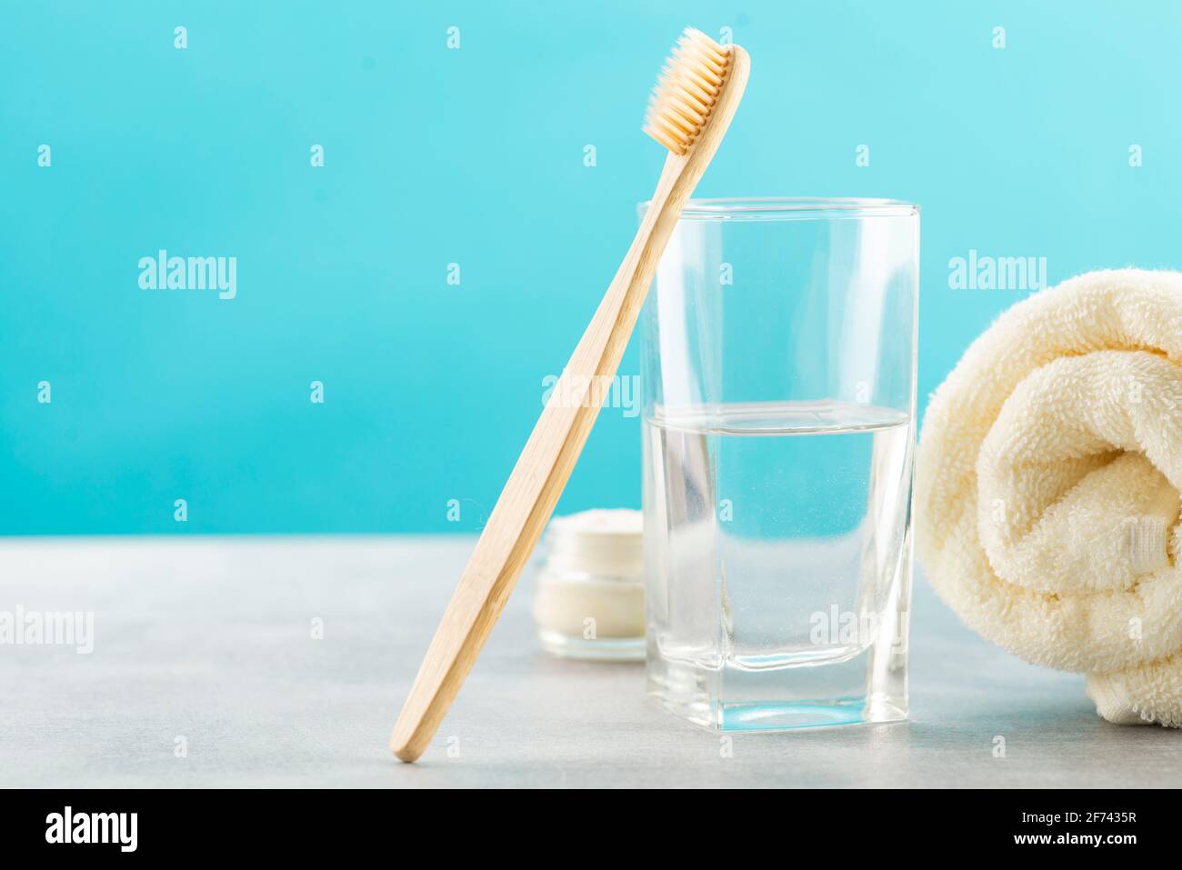 Eine Bambuszahnbürste, ein Glas Wasser, ein weißes Baumwolltuch und Zahnbürstenpulver in einem Glas. Biologisch abbaubare Körperpflegeprodukte. Kein Kunststoffkonzept Stockfoto