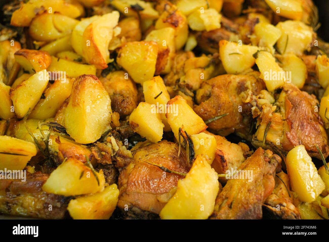 Schmackhaftes gebratenes Huhn und Kartoffeln aus der Nähe, fette Küche Stockfoto