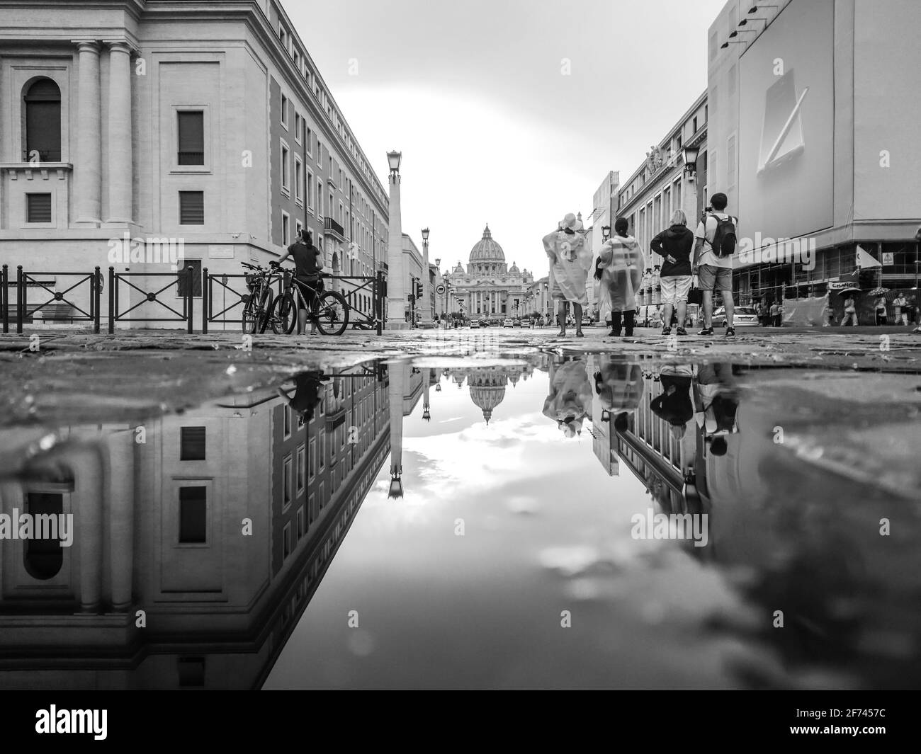 Rom, Italien - 18. August 2019: Schwarz-Weiß-Ansicht des Petersdoms in der Vatikanstadt mit Spiegelreflexion im Wasser auf der Stadtstraße. Epische Graustufen Stockfoto