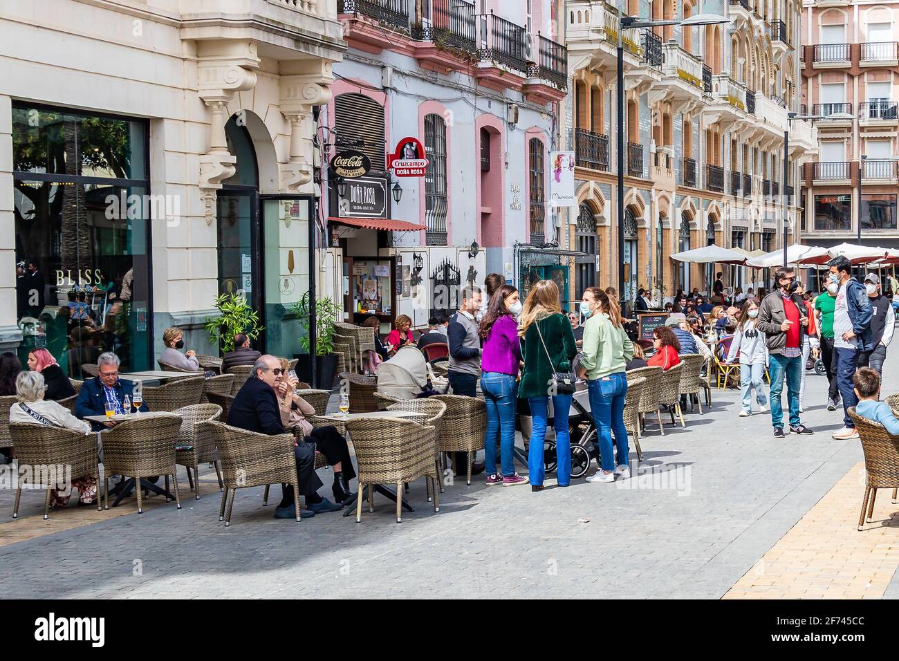 Huelva, Spanien - 1. April 2021: Menschen, die auf der Terrasse eines Cafés und einer Bar auf dem Platz Plaza de las Monjas (Nonnen-Platz) von Huelva sitzen, tragen ein p Stockfoto