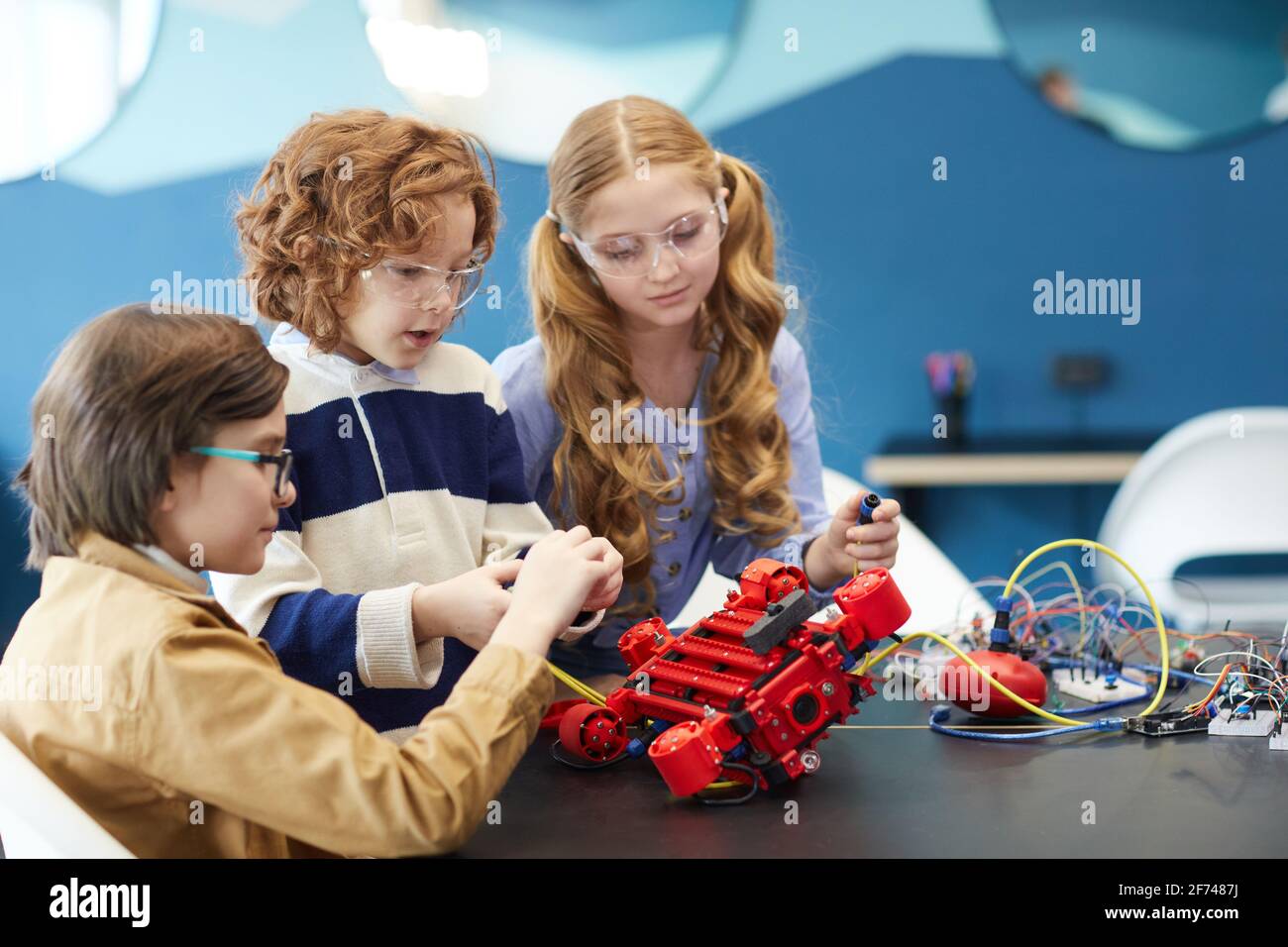 Portrait von drei niedlichen Kindern, die beim gemeinsamen Bauen Roboter bauen Engineering-Klasse in der Entwicklungsschule Stockfoto