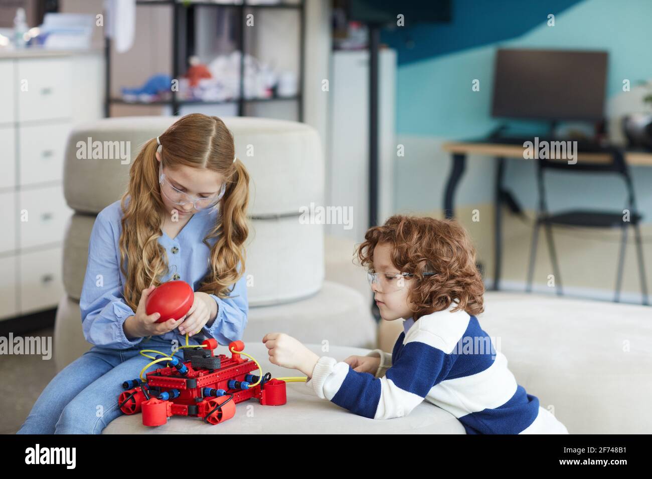 Portrait von zwei Kindern, die während des Ingenieursschulunterschots im modernen Schulinnenraum mit der Robotermaschine spielen, Kopierraum Stockfoto