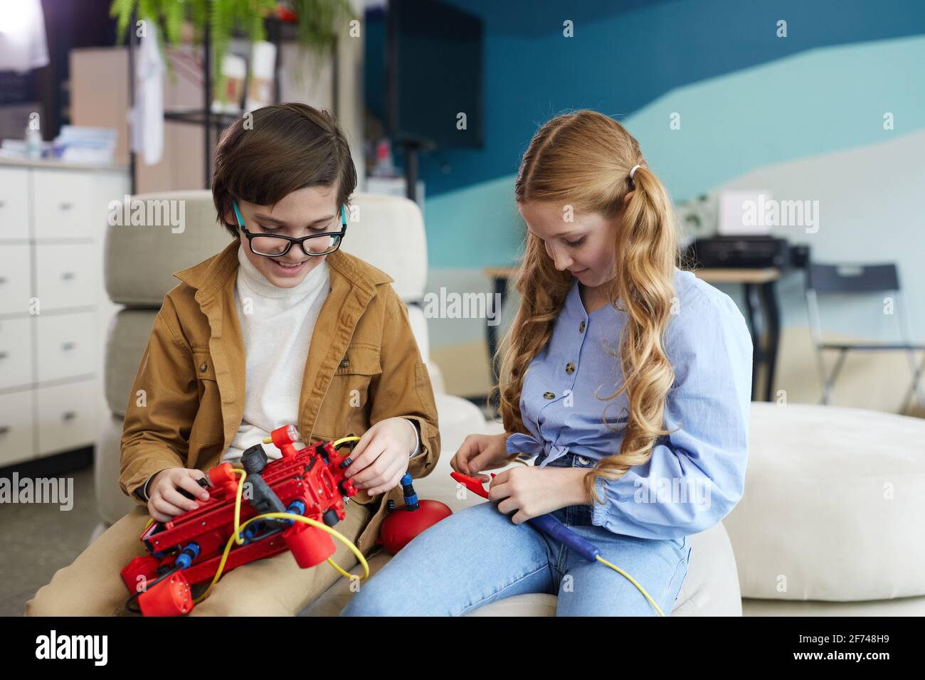 Porträt von zwei Kindern, die während des Ingenieursschulunterschots im modernen Schulinnenraum mit der Robotermaschine spielen, Kopierraum Stockfoto