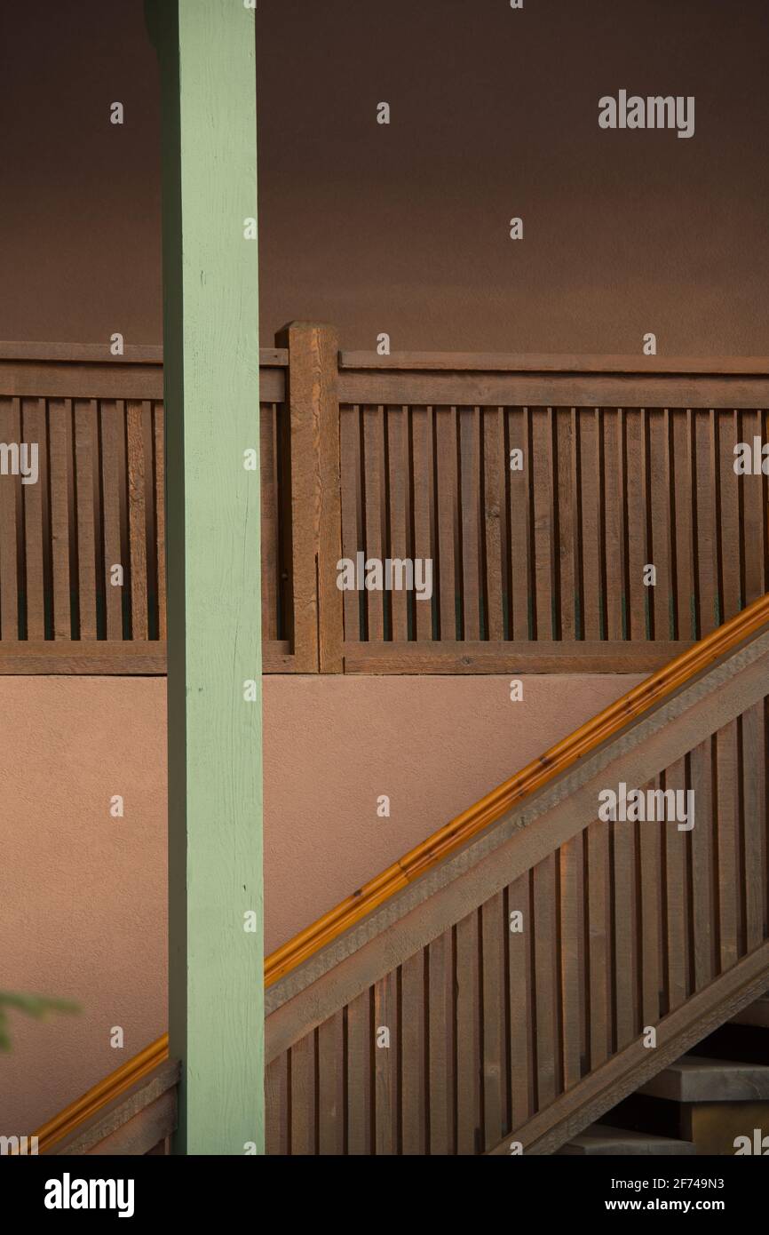 Holztreppe Gehäuse von außen Haus oder Wohnung gegen Pfirsich Farbige Außenbetonwand und grün lackierter aufrechter Stützstock Anzeigen von Winkeln Stockfoto