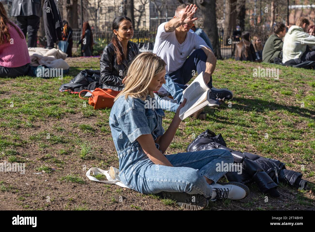 NEW YORK, NEW YORK - 3. APRIL: Eine Frau liest am 3. April 2021 im Tompkins Square Park in New York City ein Buch. Stockfoto