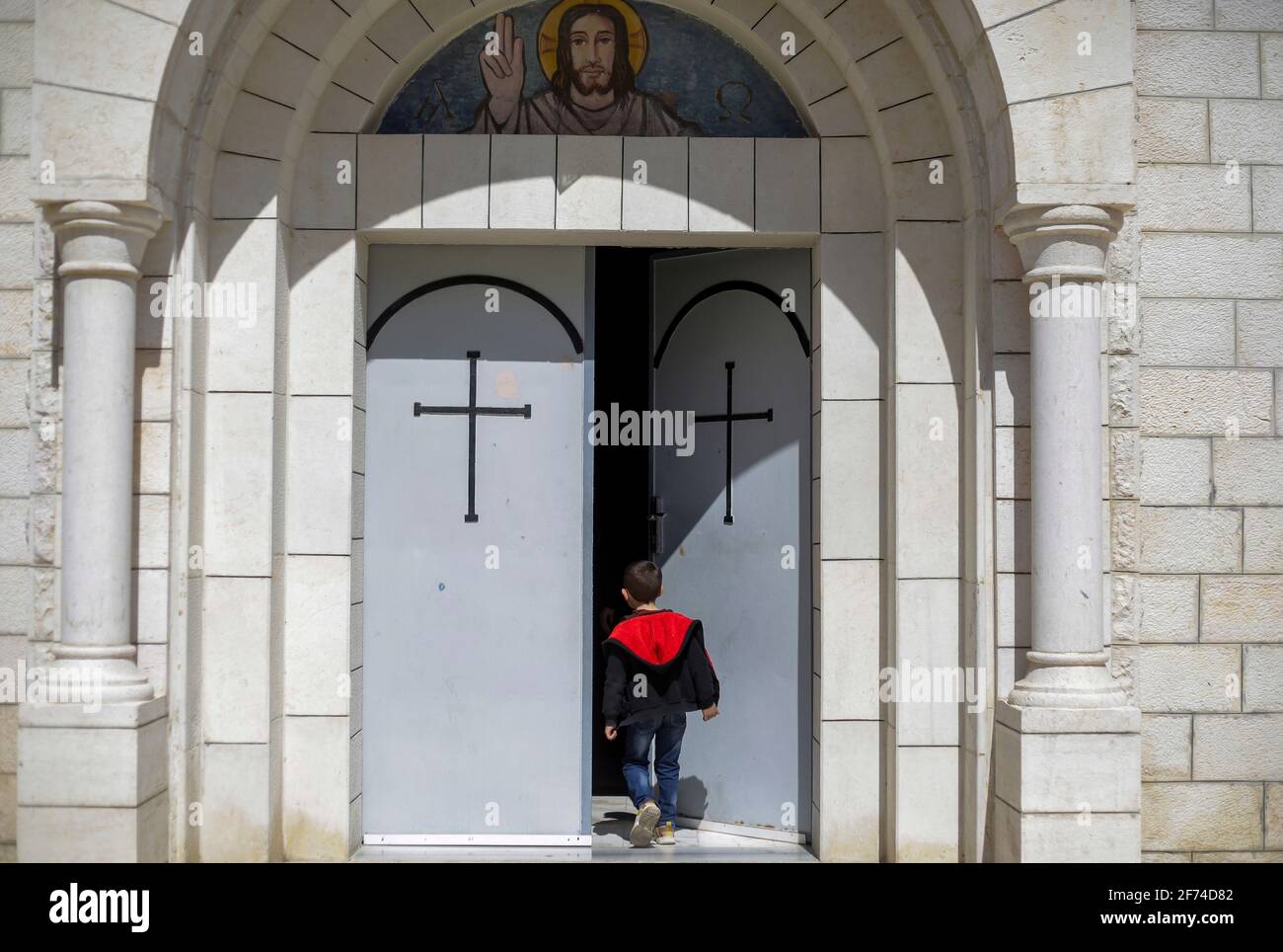 Ein palästinensisches christliches Kind, das während der Ostermesse am Eingang der römisch-katholischen Kirche der Heiligen Familie gesehen wurde. Ostervigil, auch als Ostervigil oder große Ostervigil bezeichnet, Ist eine Liturgie, die in traditionellen christlichen Kirchen als erste offizielle Feier der Auferstehung Jesu abgehalten wird. Historisch gesehen werden während dieser Liturgie Menschen getauft und Erwachsene Katechumenen in voller Gemeinschaft mit der Kirche aufgenommen. Es wird in den Stunden der Dunkelheit zwischen Sonnenuntergang am Karsamstag und Sonnenaufgang am Ostertag am häufigsten am Abend des Karsamstags oder Mitte gehalten Stockfoto