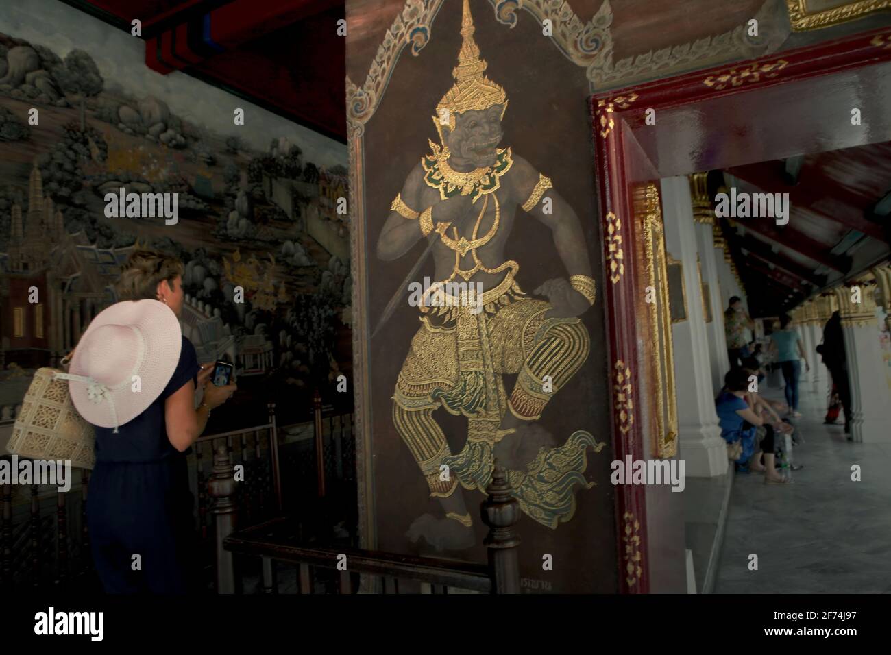 Ein Besucher, der die Gasse betreten hat, in der sich eine Galerie mit Wandgemälden, die Ramakien (thailändische Version des Ramayana-Epos) darstellen, im Wat Phra Kaew (Tempel des Smaragd-Buddha) im Grand Palace-Komplex in Bangkok, Thailand, befindet. Thailand ist das erste südostasiatische Land, das Quarantänebeschränkungen von 14 Tagen auf 10 Tage reduziert hat, um die Erholung seines Tourismussektors zu beschleunigen, so South China Morning Post am 2. April 2021. Die Entscheidung wurde getroffen, den Erholungsprozess zu beschleunigen, der zuvor von der Weltbank als „langsame Rückkehr“ prognostiziert wurde. Stockfoto