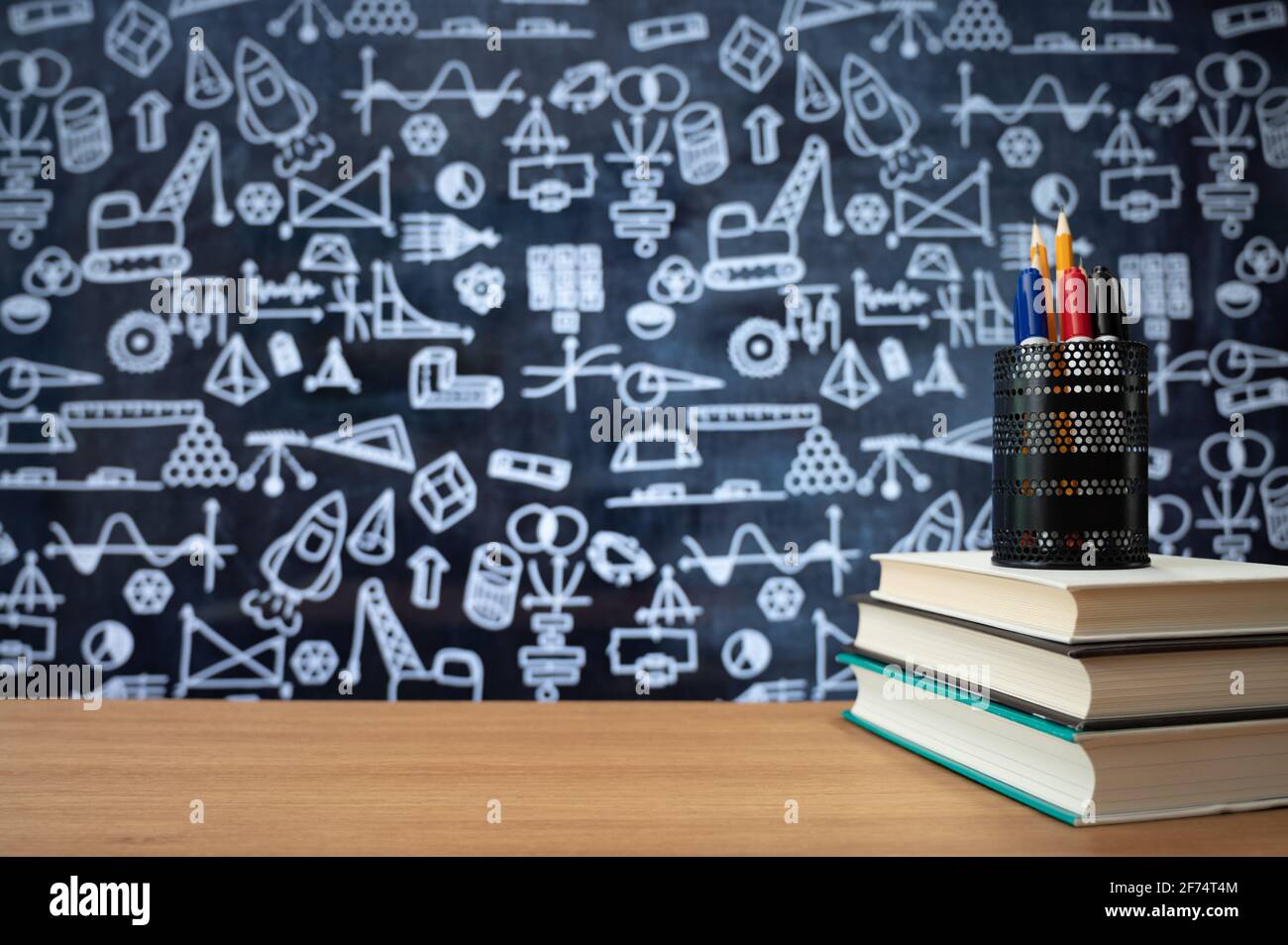 Tafel mit handgezeichneten Symbolen für mathematische Berechnungen. Bücher auf dem Schreibtisch gestapelt. Bildungskonzept. Stockfoto
