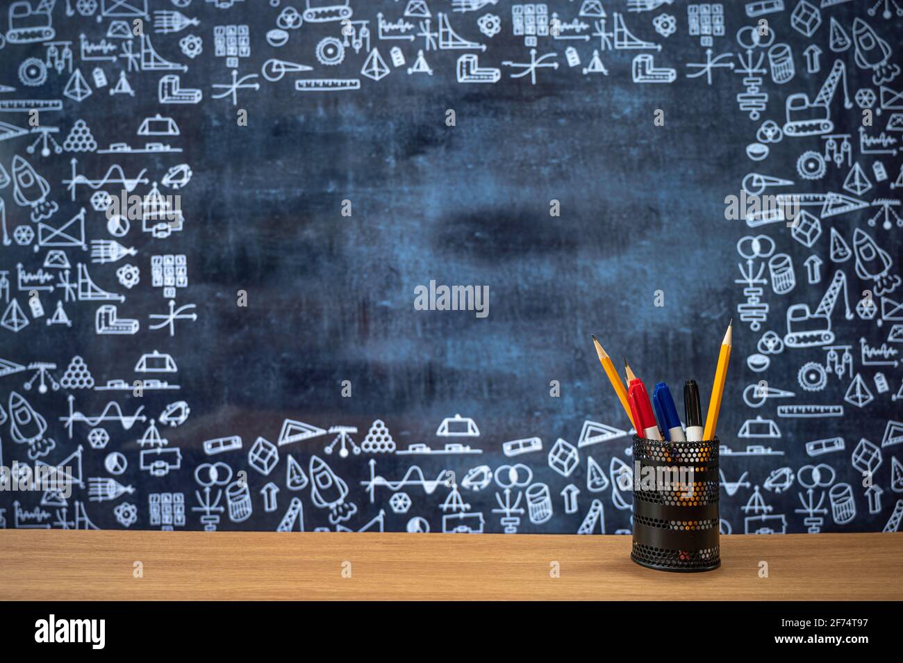Tafel mit handgezeichneten Symbolen für mathematische Berechnungen. Federmäppchen auf dem Schreibtisch. Bildungskonzept. Stockfoto