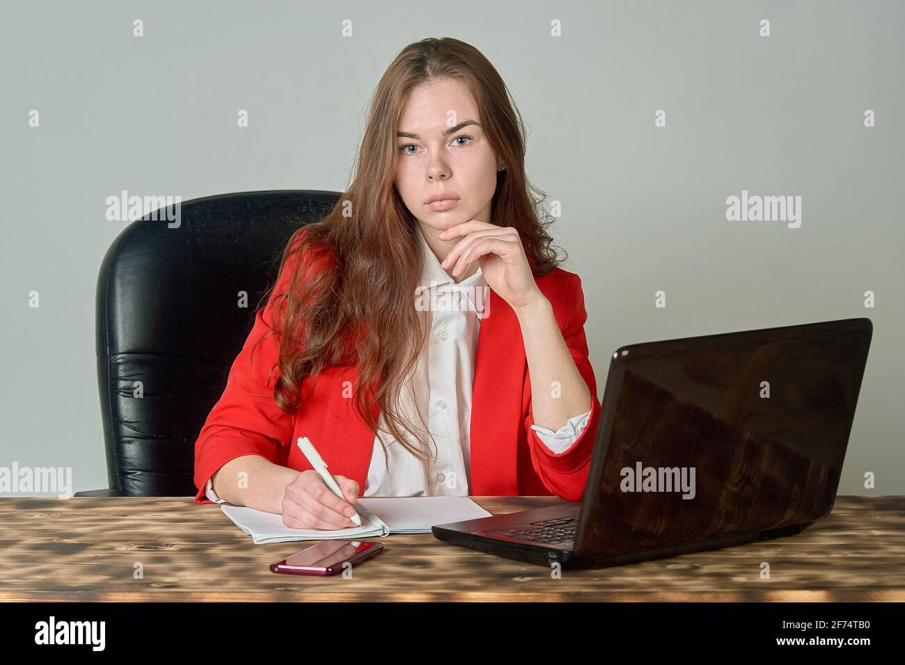 Eine Frau, die an einem Schreibtisch sitzt und mit einem Laptop arbeitet Und Notizblock Stockfoto