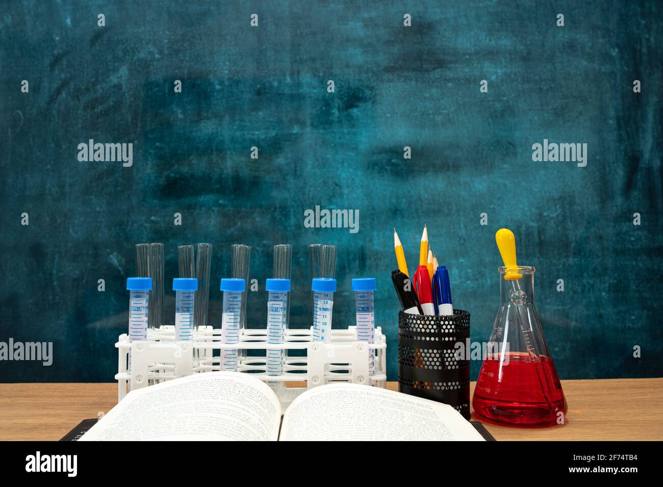 Bücher und wissenschaftliche Experimentwerkzeuge auf dem Schreibtisch. Leere Tafel. Bildungskonzept. Stockfoto