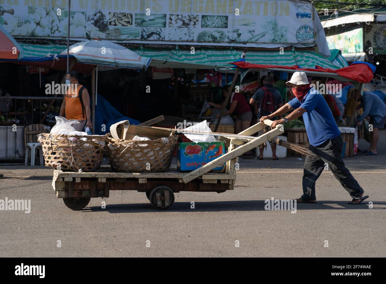Ein Mann schiebt einen Holzwagen mit Körben in einem Marktgebiet, Cebu City, Philippinen Stockfoto