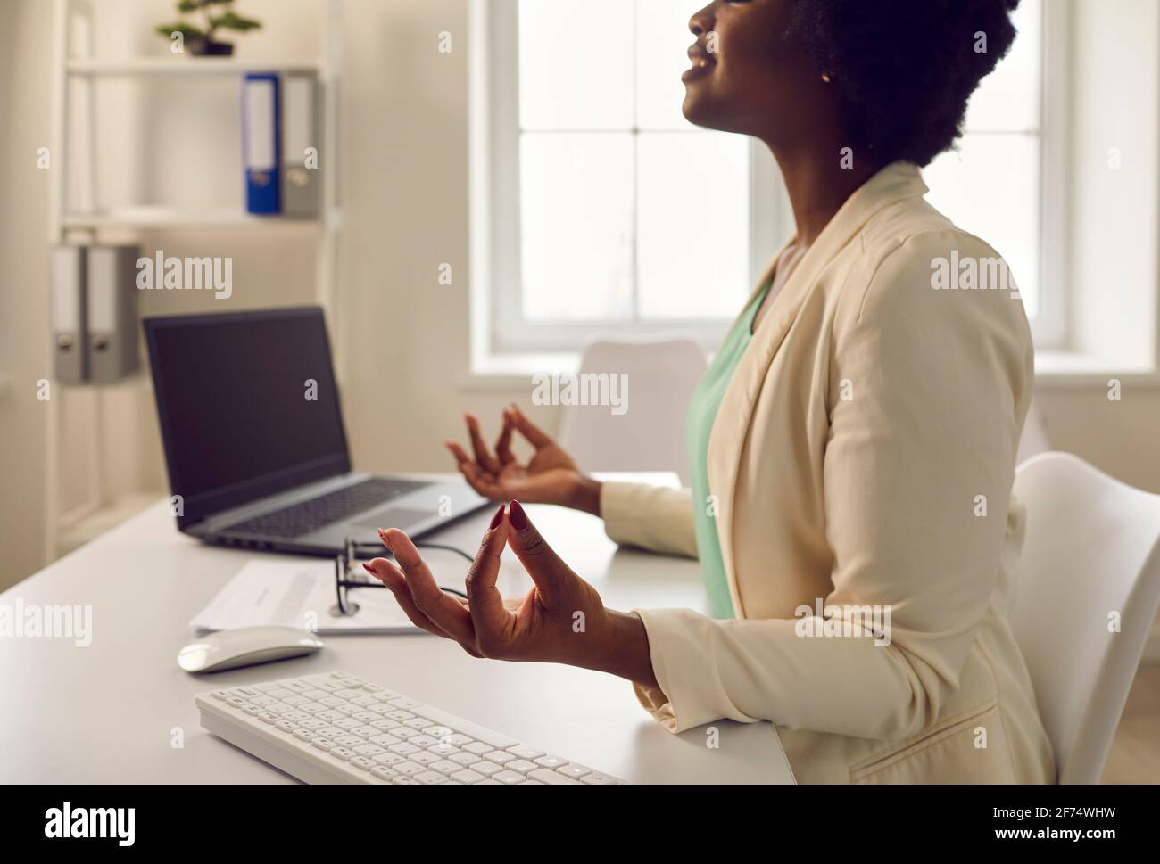 afroamerikanische Angestellte meditieren ruhig am Schreibtisch Hochformat Stockfoto