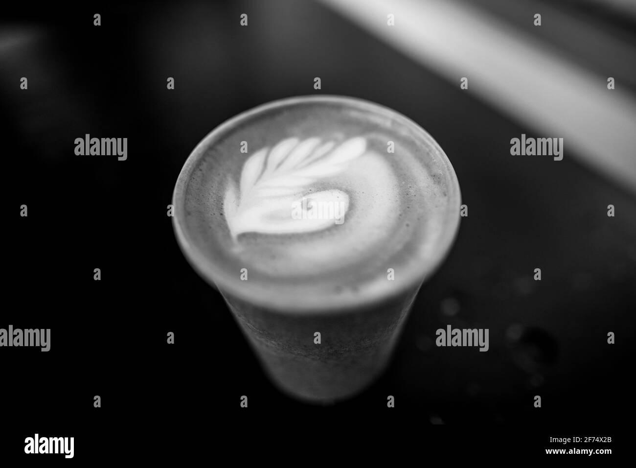 Bild mit geringer Schärfentiefe (selektiver Fokus) und Details eines dekorierten Kaffees in einer Papiertasse. Stockfoto