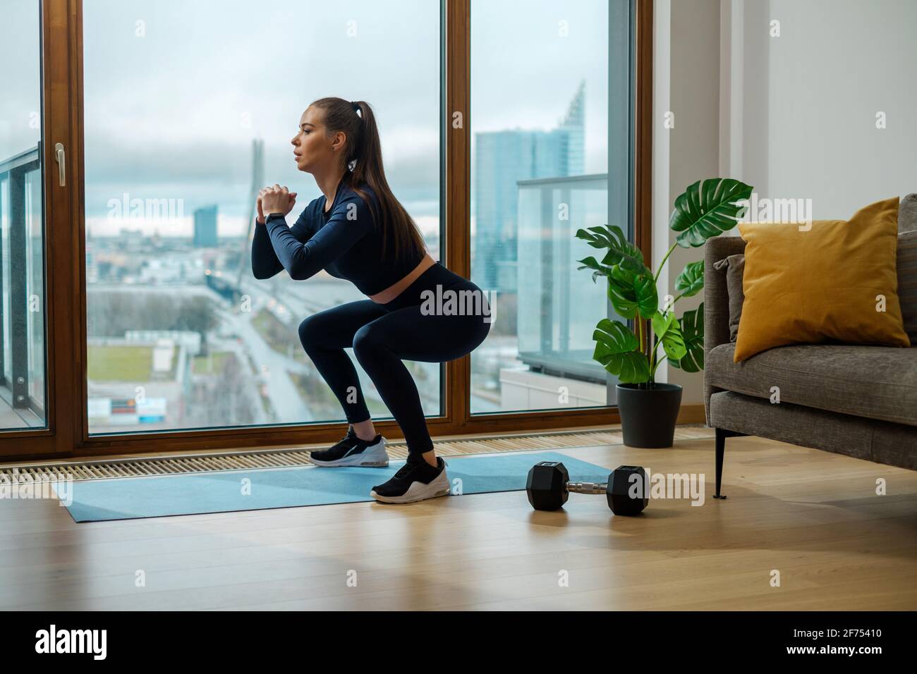 Schlanke Brünette Frau im grünen Trainingsanzug in Hocke Position Stockfoto