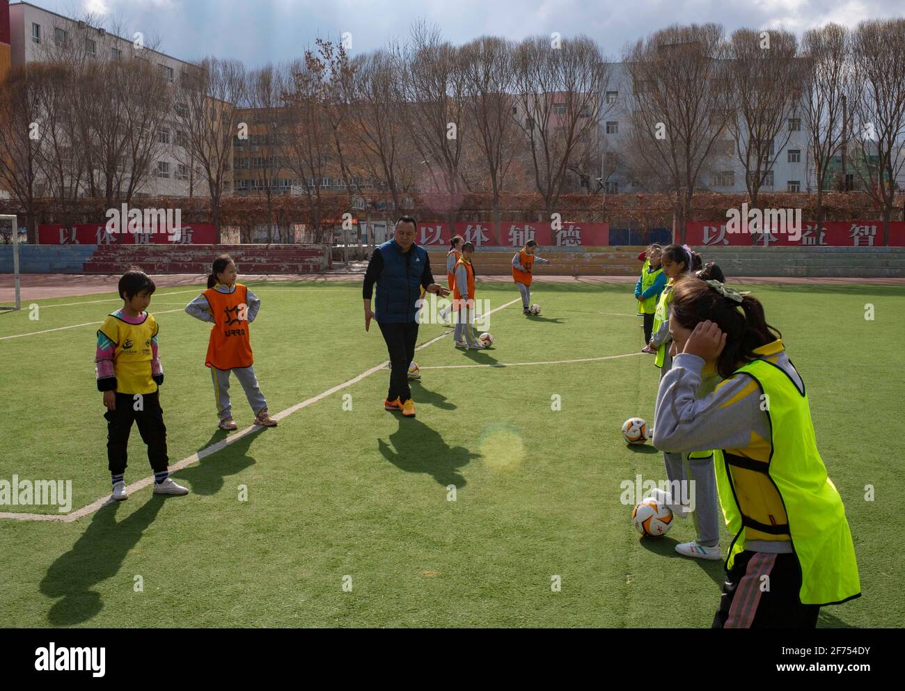 (210405) -- SHAWAN, 5. April 2021 (Xinhua) -- Xia Songhao (3. L) und seine Schüler nehmen an einer Trainingseinheit in der Stadt Shawan, nordwestlich der Autonomen Region Xinjiang Uygur in China, am 31. März 2021 Teil. 2011 wurde die Mädchen-Fußballmannschaft der Grundschule Nr. 2 in Shawan City gegründet. Unter der Leitung von Xia Songhao, der seit fast zehn Jahren Fußball auf dem Campus trainiert, hat sich die Fußballmannschaft der Mädchen zu einer vielfältigen Gruppe aus multiethnischen Spielern entwickelt. Nach kontinuierlichem und strengem Training hat das Team hervorragende Ergebnisse erzielt und eine Reihe von Meisterschaften auf verschiedenen Ebenen gewonnen Stockfoto