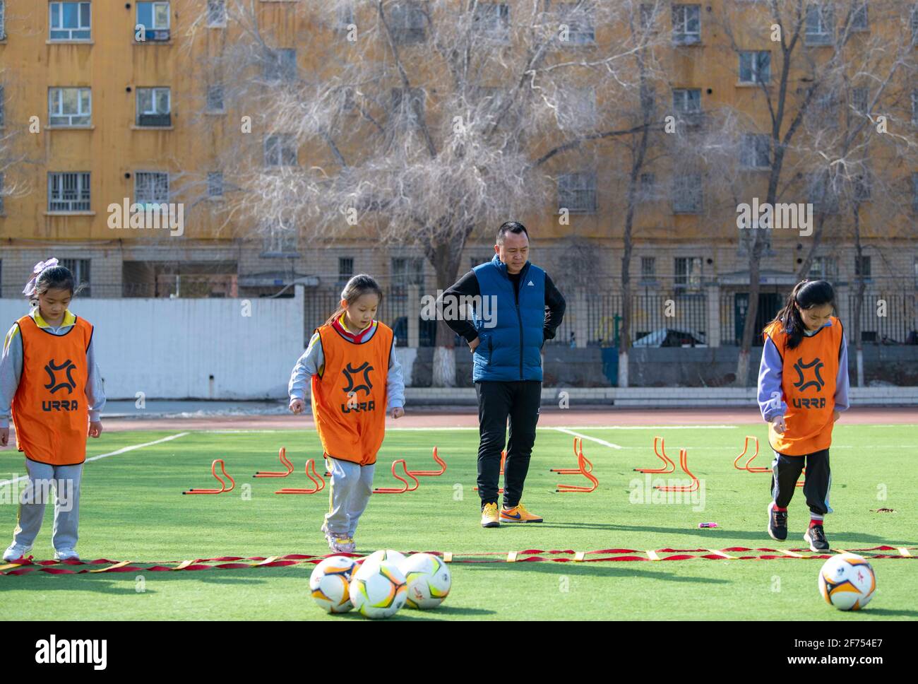 (210405) -- SHAWAN, 5. April 2021 (Xinhua) -- Xia Songhao (2. R) und seine Schüler nehmen am 1. April 2021 an einer Trainingseinheit in der Stadt Shawan, der Autonomen Region Xinjiang Uygur im Nordwesten Chinas, Teil. 2011 wurde die Mädchen-Fußballmannschaft der Grundschule Nr. 2 in Shawan City gegründet. Unter der Leitung von Xia Songhao, der seit fast zehn Jahren Fußball auf dem Campus trainiert, hat sich die Fußballmannschaft der Mädchen zu einer vielfältigen Gruppe aus multiethnischen Spielern entwickelt. Nach kontinuierlichem und strengem Training hat das Team hervorragende Ergebnisse erzielt und eine Reihe von Meisterschaften auf verschiedenen Ebenen gewonnen. Stockfoto