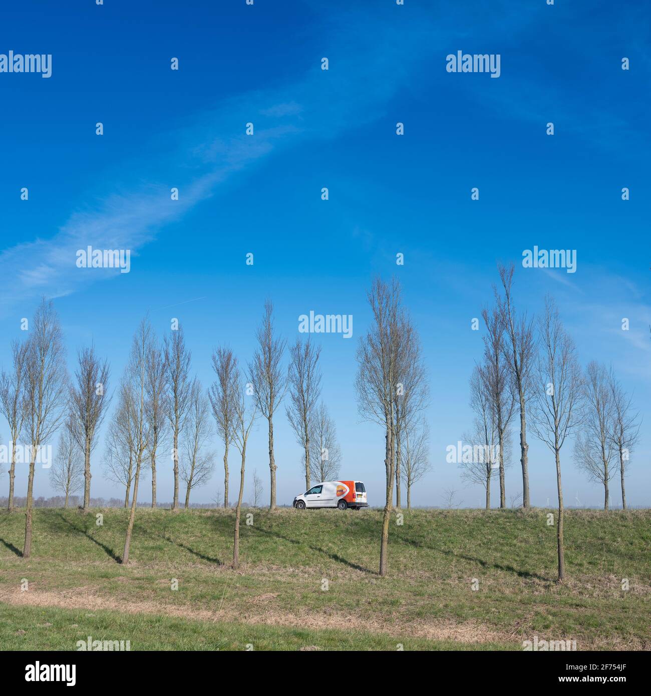 Auto der Postzustellung auf dem Deich von goeree overflkakkee in Die niederlande unter blauem Himmel Stockfoto