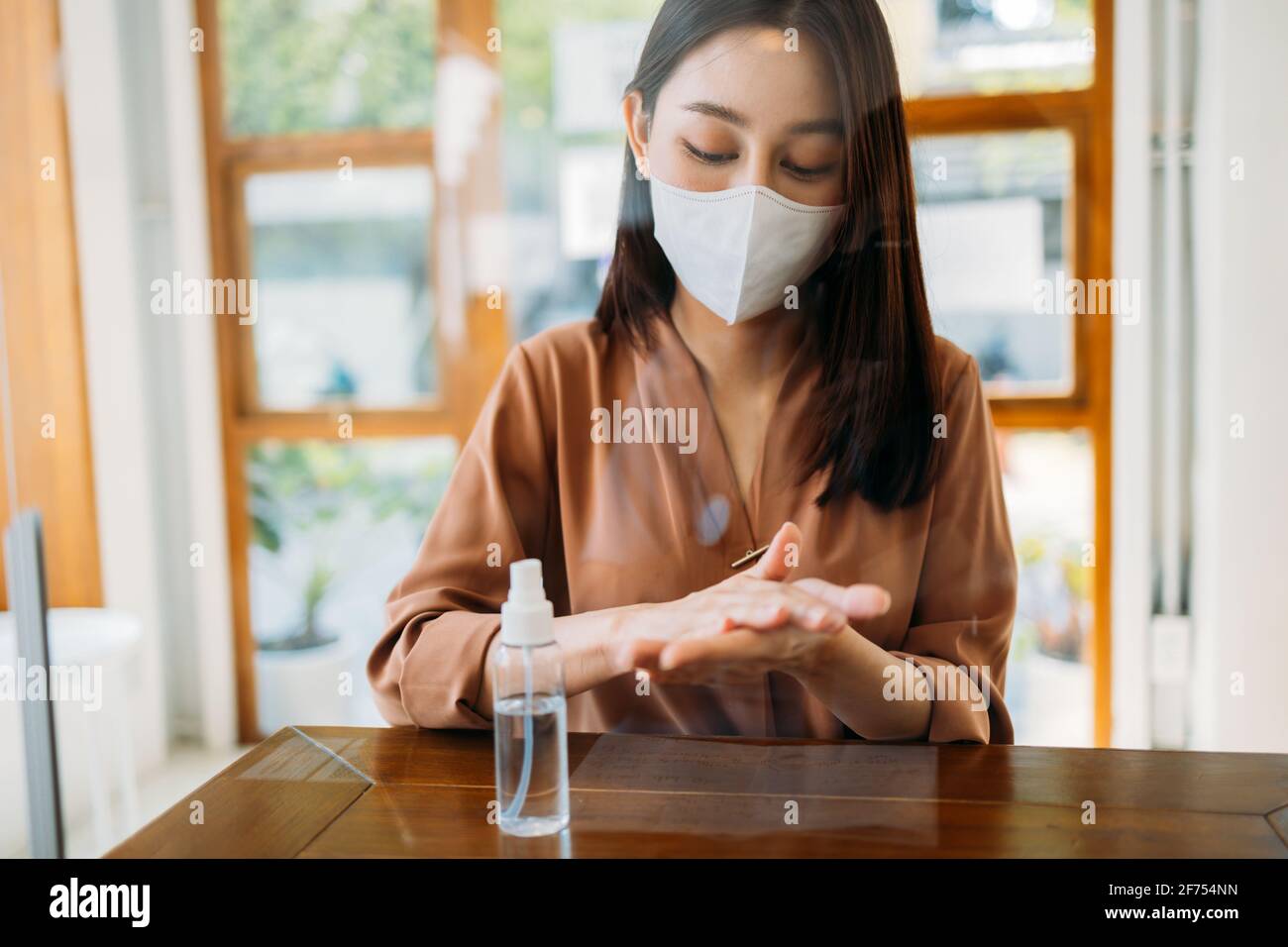 Junge asiatische Frau trägt covid-19 Gesichtsschutz Maske und Waschen Und die Desinfektion von Händen mit einem medizinischen Händedesinfektionsmittel aus Sicherheitsgründen Und Vorsorge gegen Viren Stockfoto