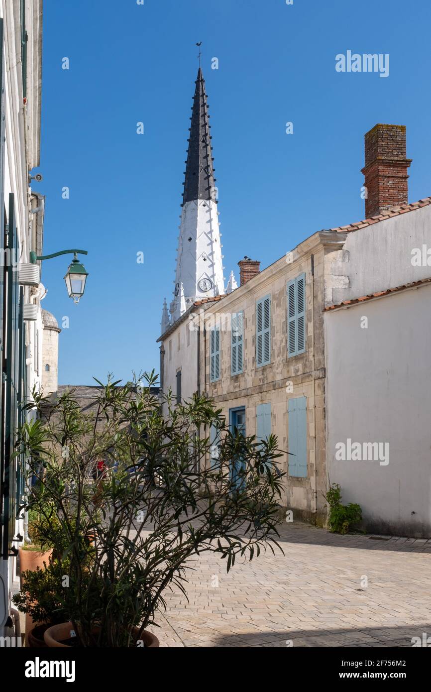 Blick auf eine leere Straße und den Kirchturm von Ars-en-Ré, aufgenommen auf der Isle of Rhé an einem sonnigen späten Wintertag Stockfoto