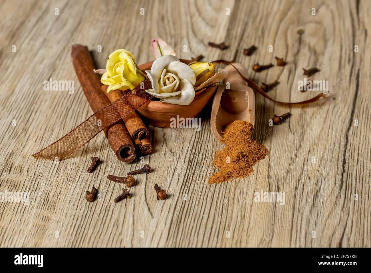 Komposition mit gemahlenem Zimt, Nelken und dekorativen Blumen auf Holztisch Stockfoto