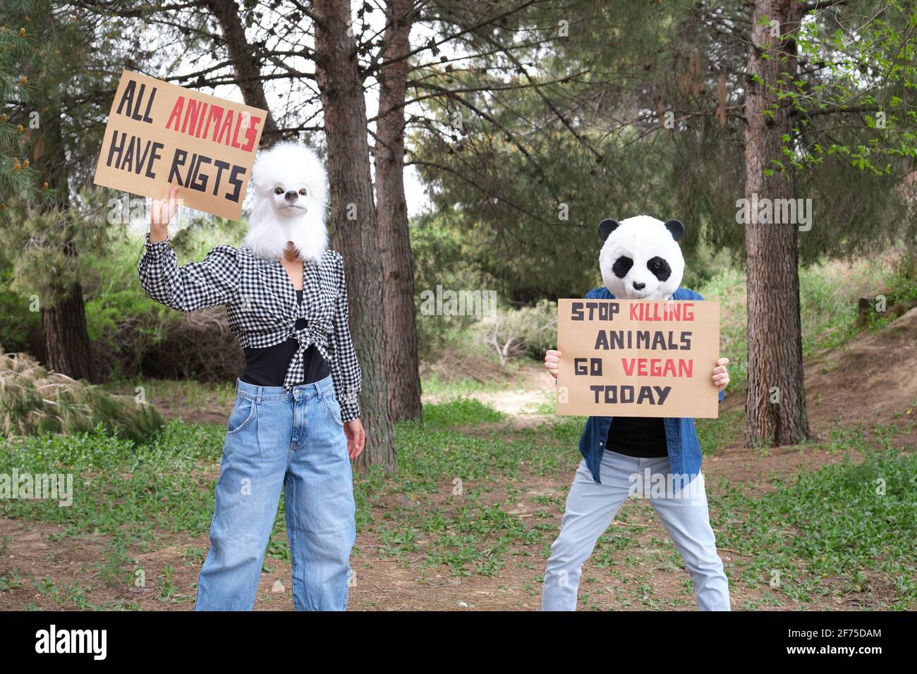 Aktivistische Demonstranten, die Tiermasken tragen, um Grausamkeit hervorzuheben und den veganen Lebensstil zu fördern. Tierrechtsproteste in einem Wald. Stockfoto