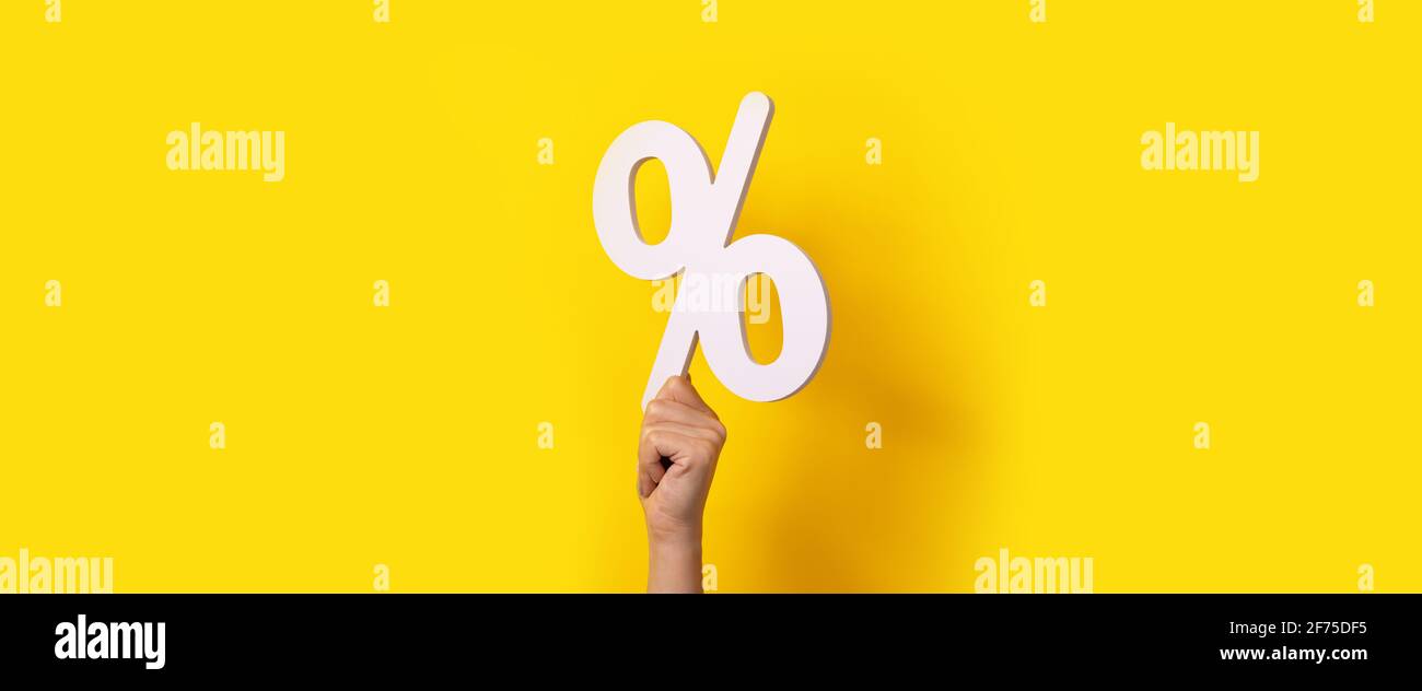 Hand hält Prozentzeichen über gelbem Hintergrund Stockfoto