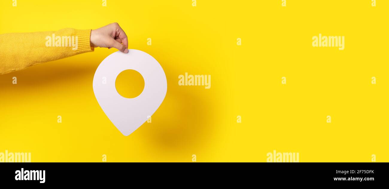 PIN-Symbol in der Hand auf gelbem Hintergrund, Panorama-Modell Stockfoto