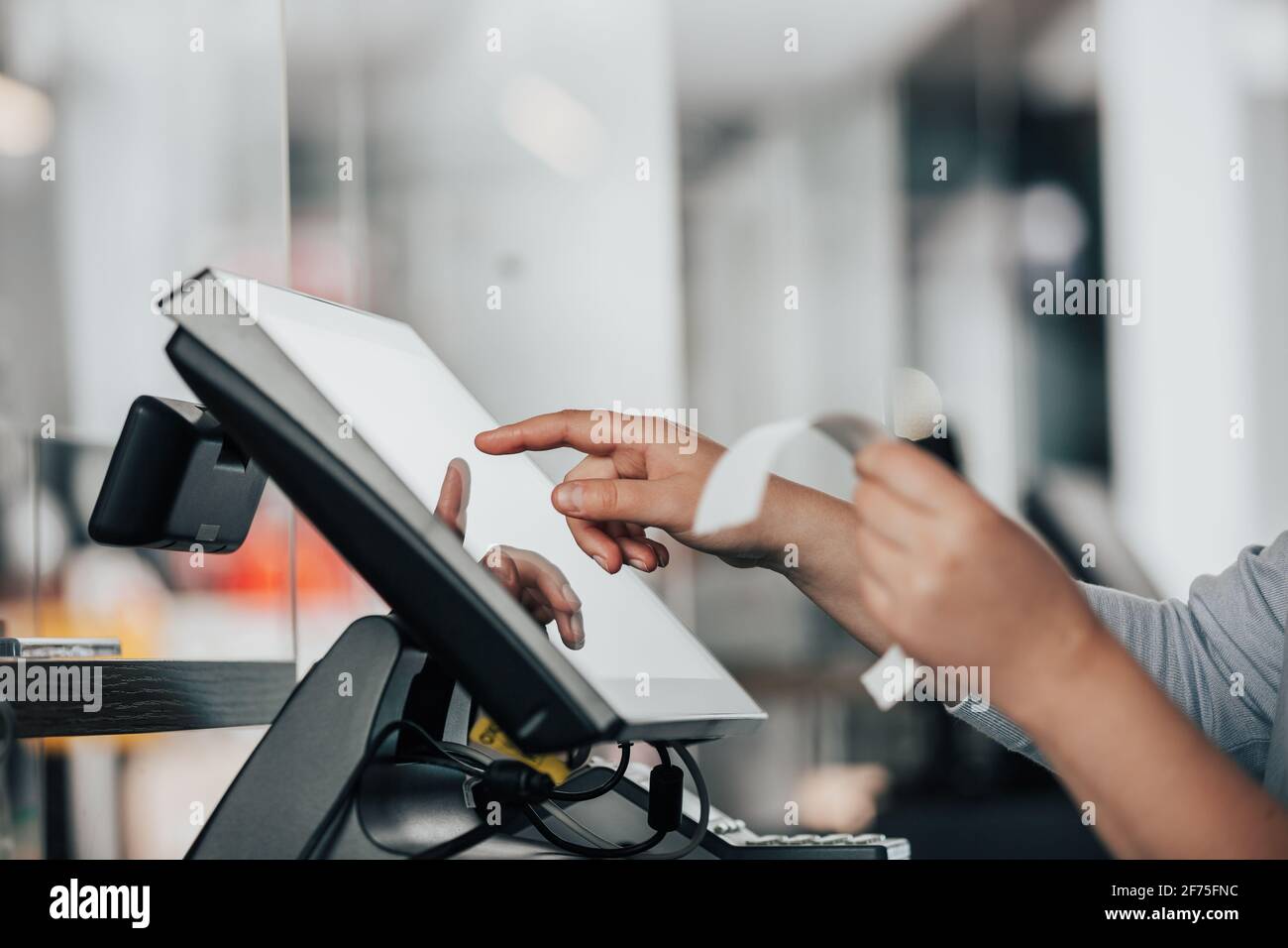 Junge Verkäuferin, die die Zahlung am Touchscreen-POS abwickl, den Verkauf an der Kasse zähle, Finanzierungskonzept Stockfoto