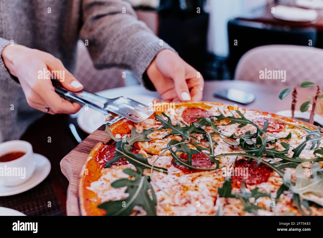 Pizza Käse Wurst Arugula Hände abgeschnitten ein Stück in einen Teller gelegt, Tee Tee Tea Party mit Pizza. Stockfoto