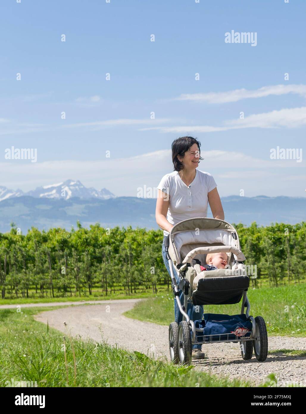 Junge Frau macht eine entspannte Tour mit ihrem kleinen Sohn Im Kinderwagen Stockfoto