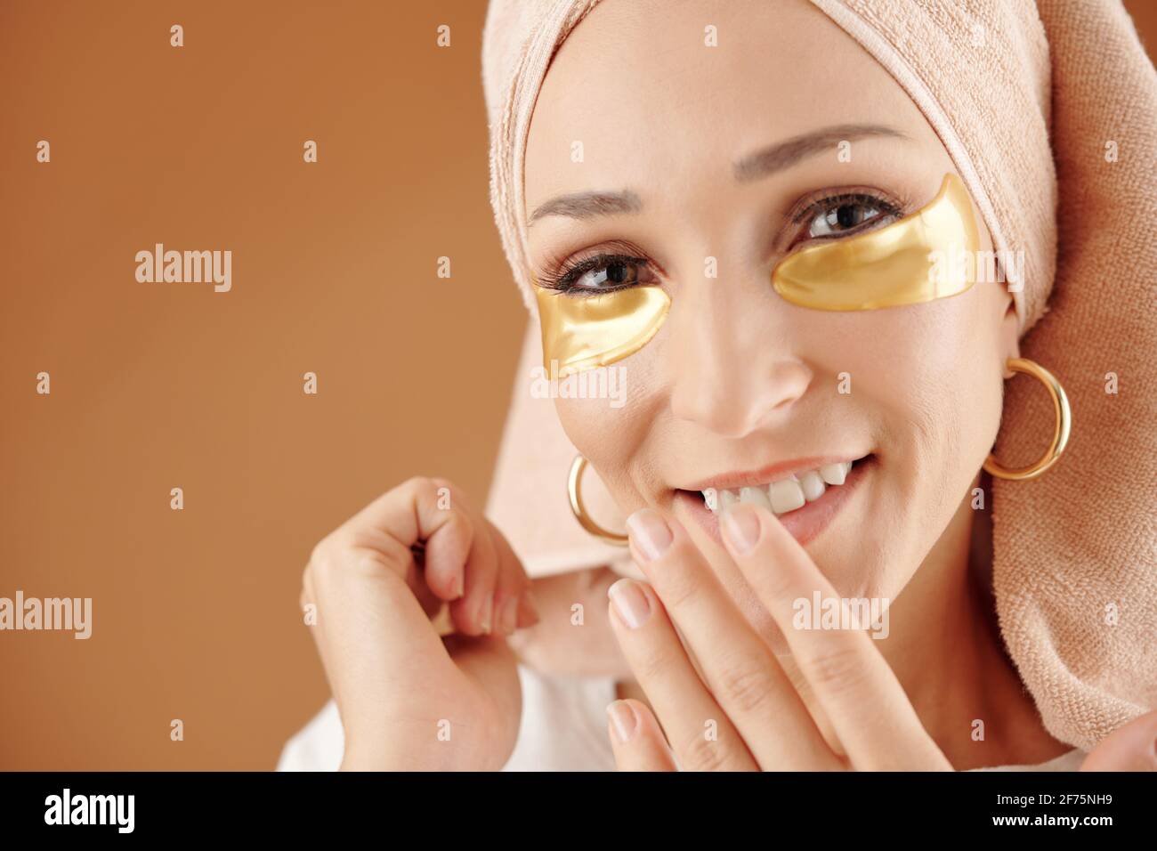 Gesicht einer attraktiven lächelnden jungen Frau mit Anti-Müdigkeit unter den Augen Maske Lächelnd und mit Blick auf die Kamera Stockfoto