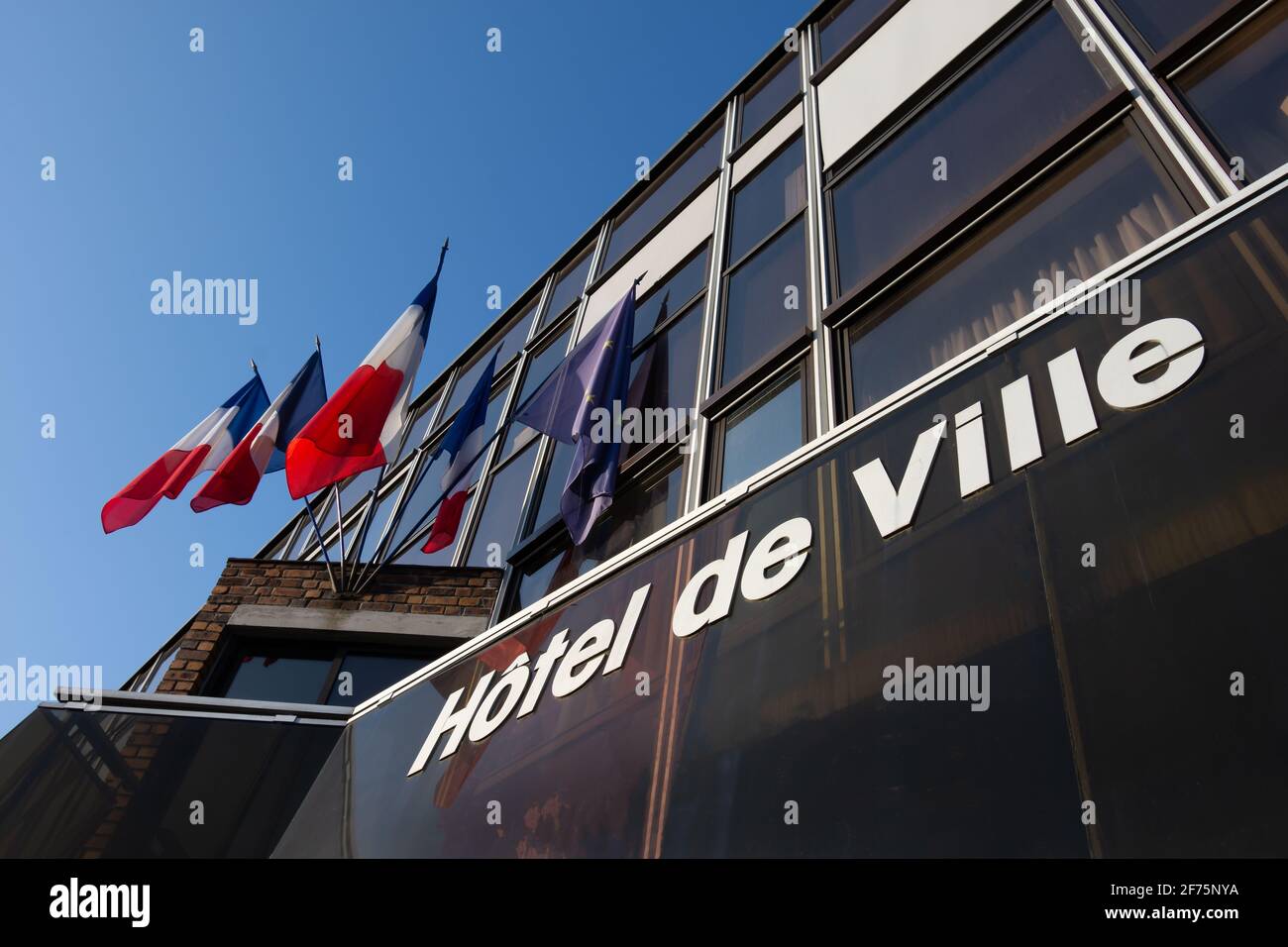 Außenansicht eines französischen Rathauses mit Fahnen und Das Wort „Hôtel de ville“ (bedeutet „Rathaus“) An der Fassade in französischer Sprache geschrieben Stockfoto
