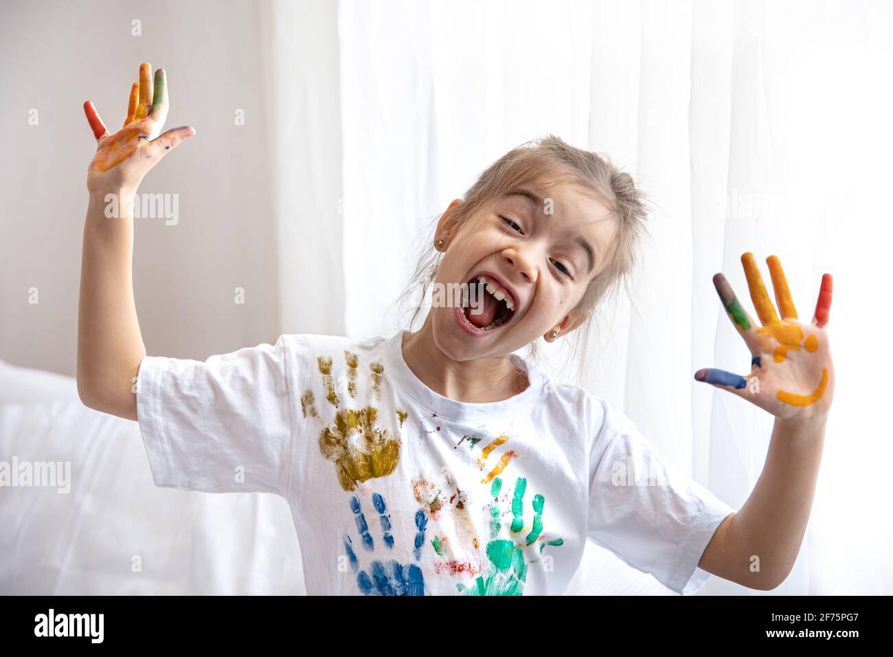 Kleines Mädchen mit Palmen in Farbe, in den Prozess der Gestaltung eines T-Shirt mit Spuren von Palmen. Kreativität und Kunst der Kinder Stockfoto