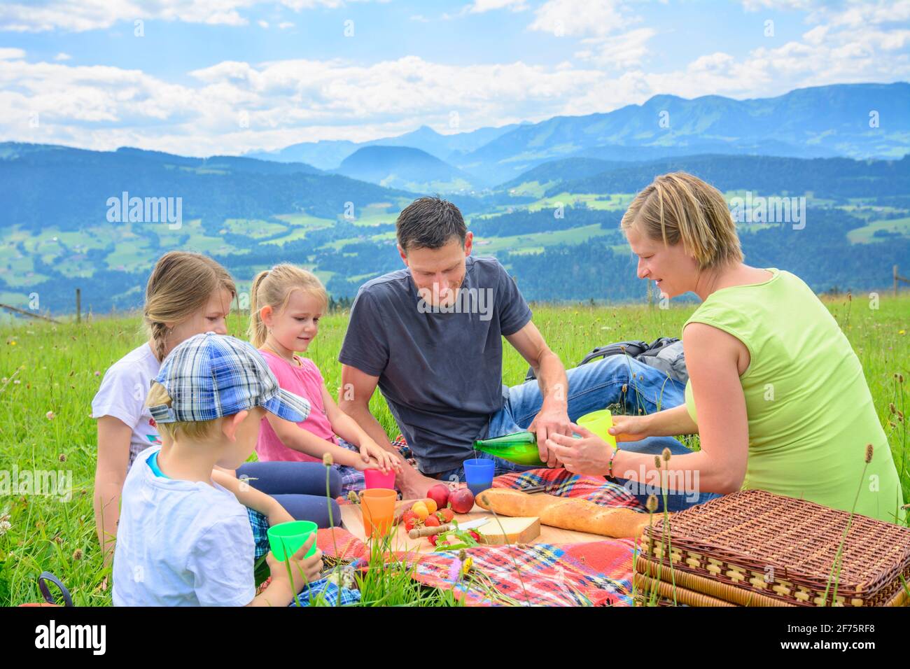 Junge Familie genießt ein Picknick in den Bergen bei einer Wanderung bei Sulzberg im Bregenzerwald. Stockfoto