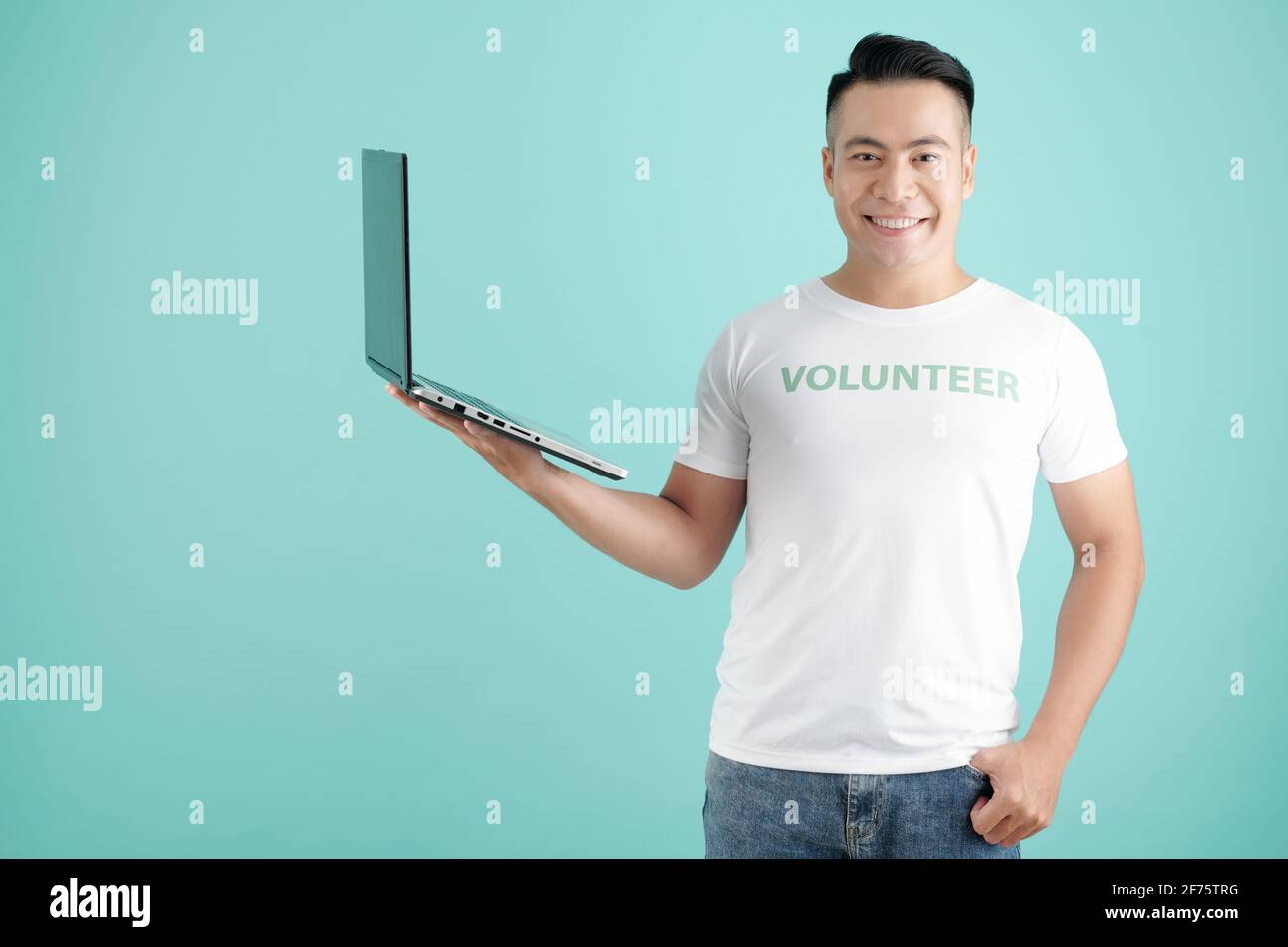 Porträt eines glücklichen jungen Mannes mit geöffnetem Laptop in der Hand Sie werden eingeladen, sich für eine Freiwilligenarbeit anzumelden Stockfoto